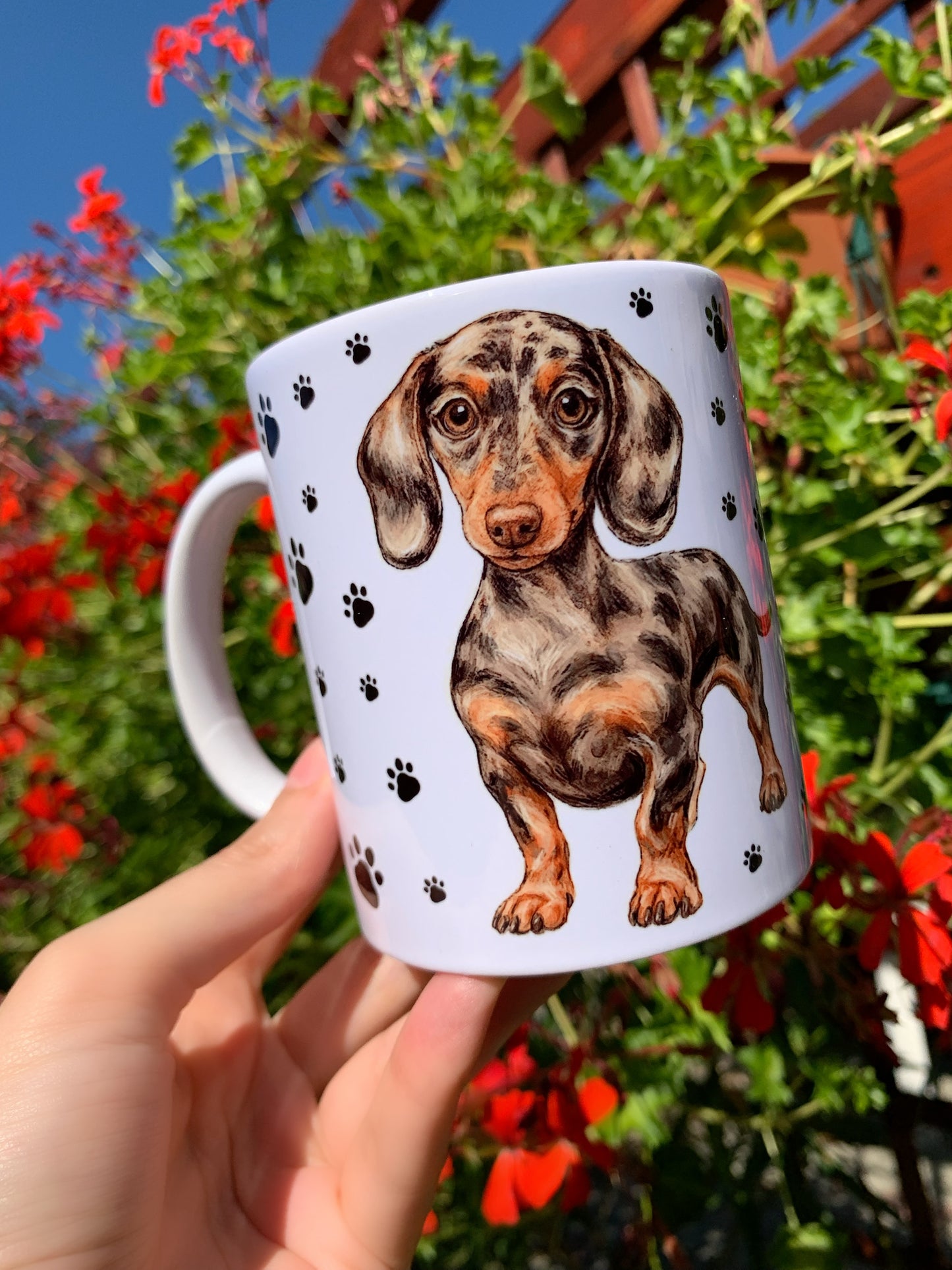 Magyar kézműves műhelyben készült tacskó mintás kerámia bögre, merle foltos mintázattal és kézzel rajzolt mancsnyomokkal.