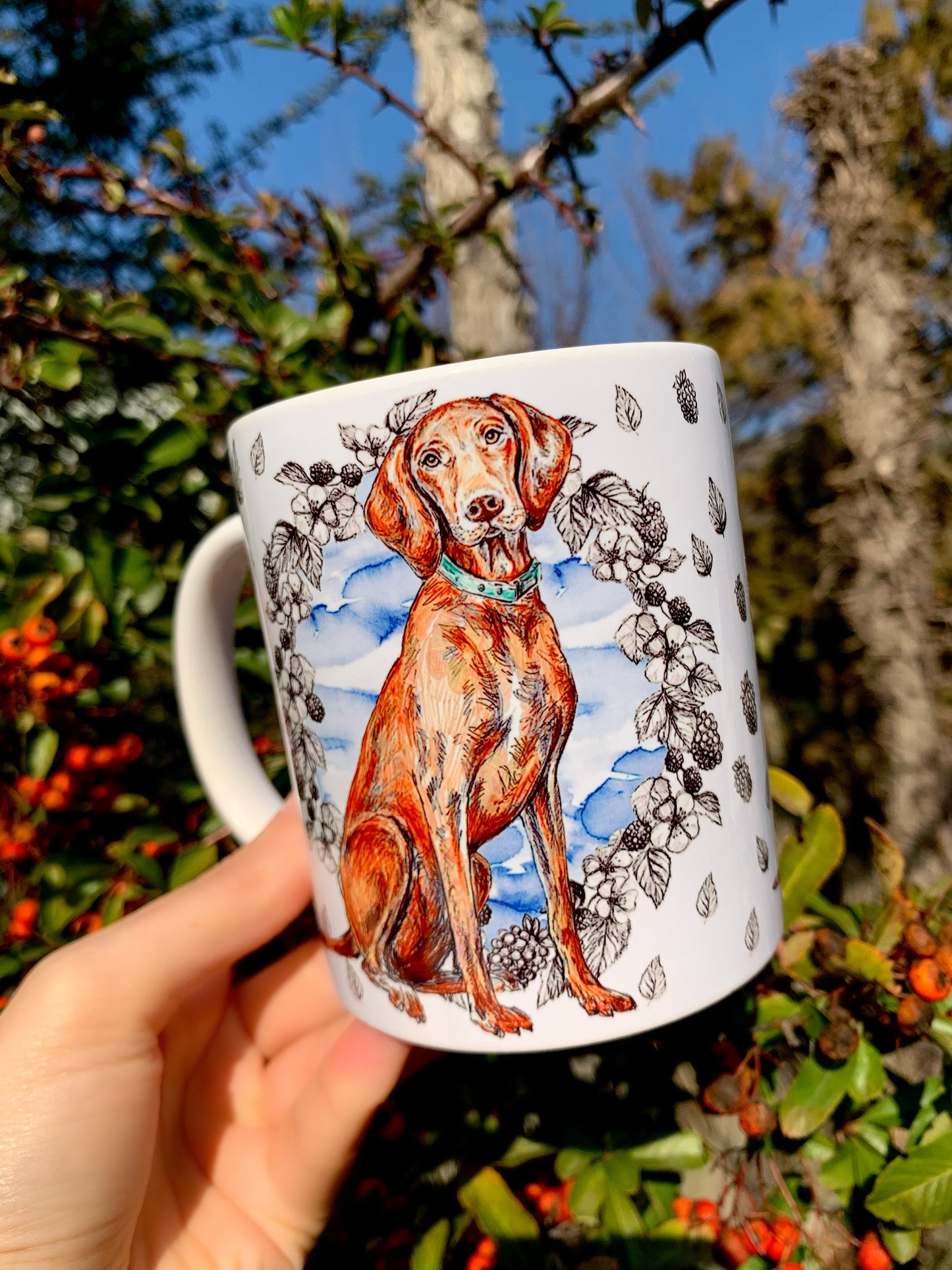 Mosolygó vizsla kutya kézzel festett illusztrációval kerámia bögrén, kék gyümölcs mintával díszített kutyás kiegészítő.