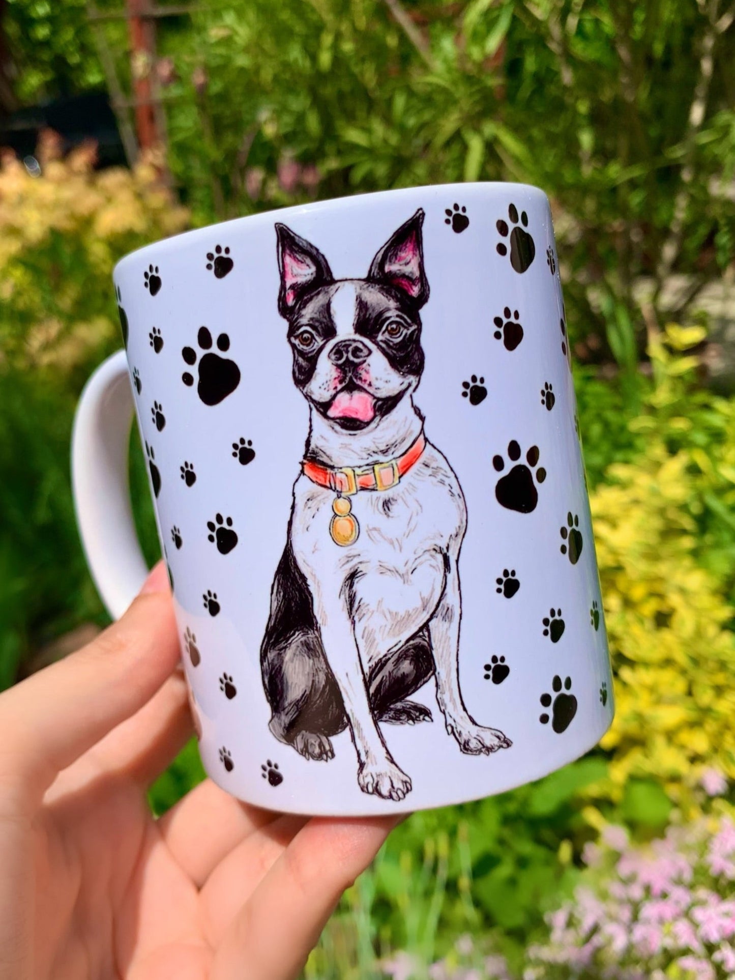 Vidám Boston terrier kutya ülve, mancs mintás háttérrel egy kerámia bögrén
