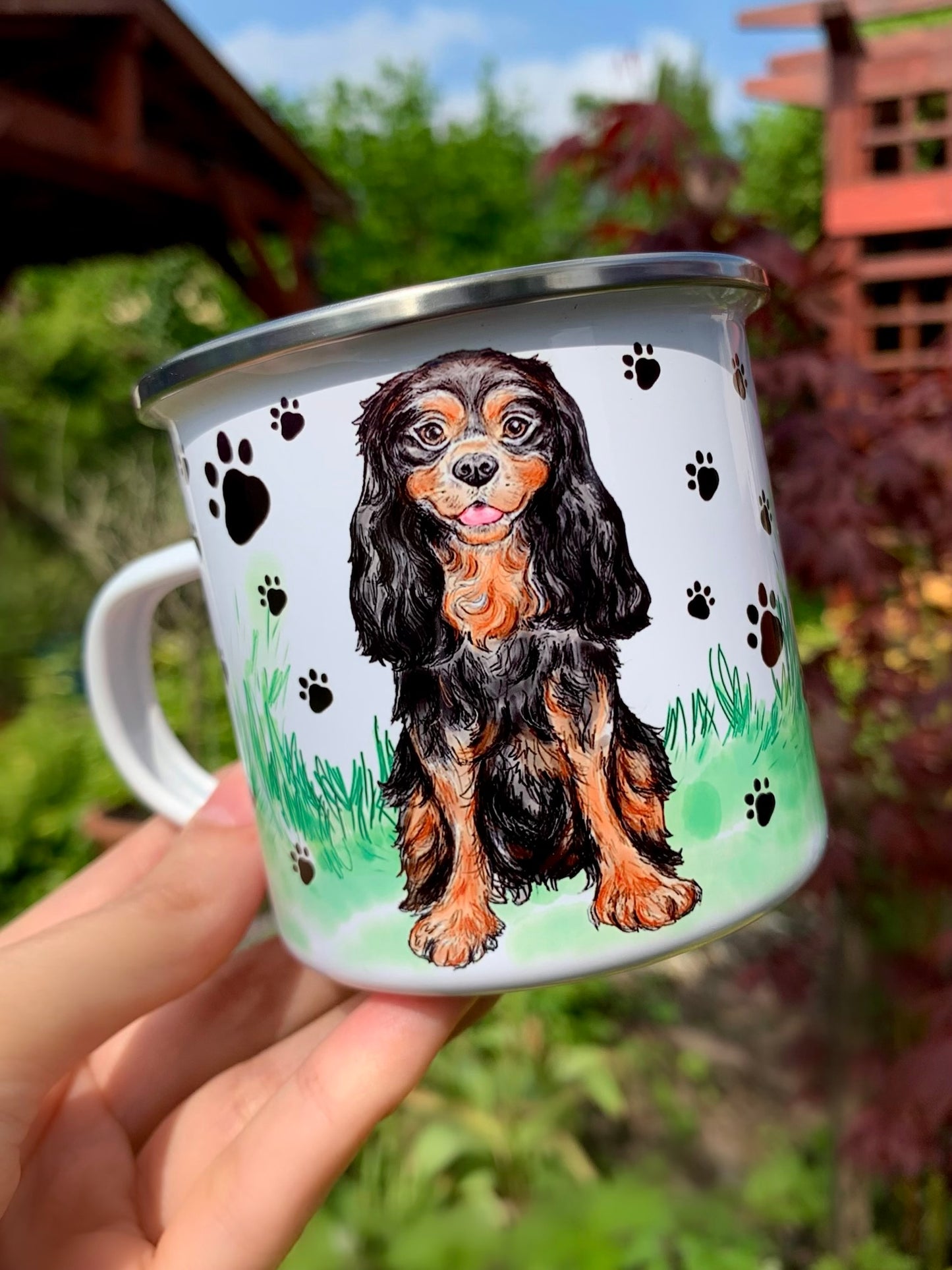 Cavalier King Charles spániel illusztráció fém bögrén, fekete mancs mintákkal és finom zöld fű rajzokkal