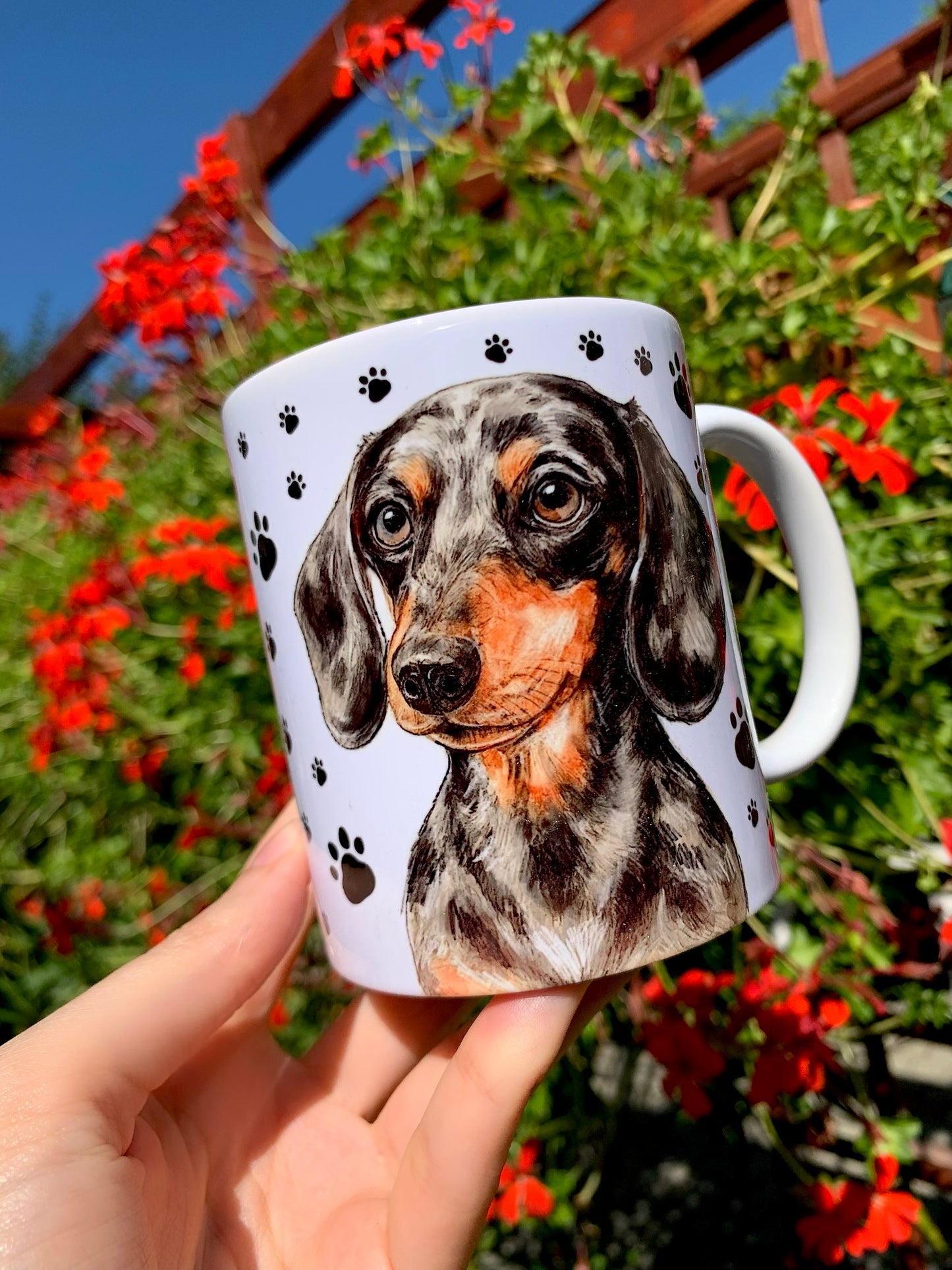 Magyar kézműves műhelyben készült tacskó mintás kerámia bögre, merle foltos mintázattal és kézzel rajzolt mancsnyomokkal.