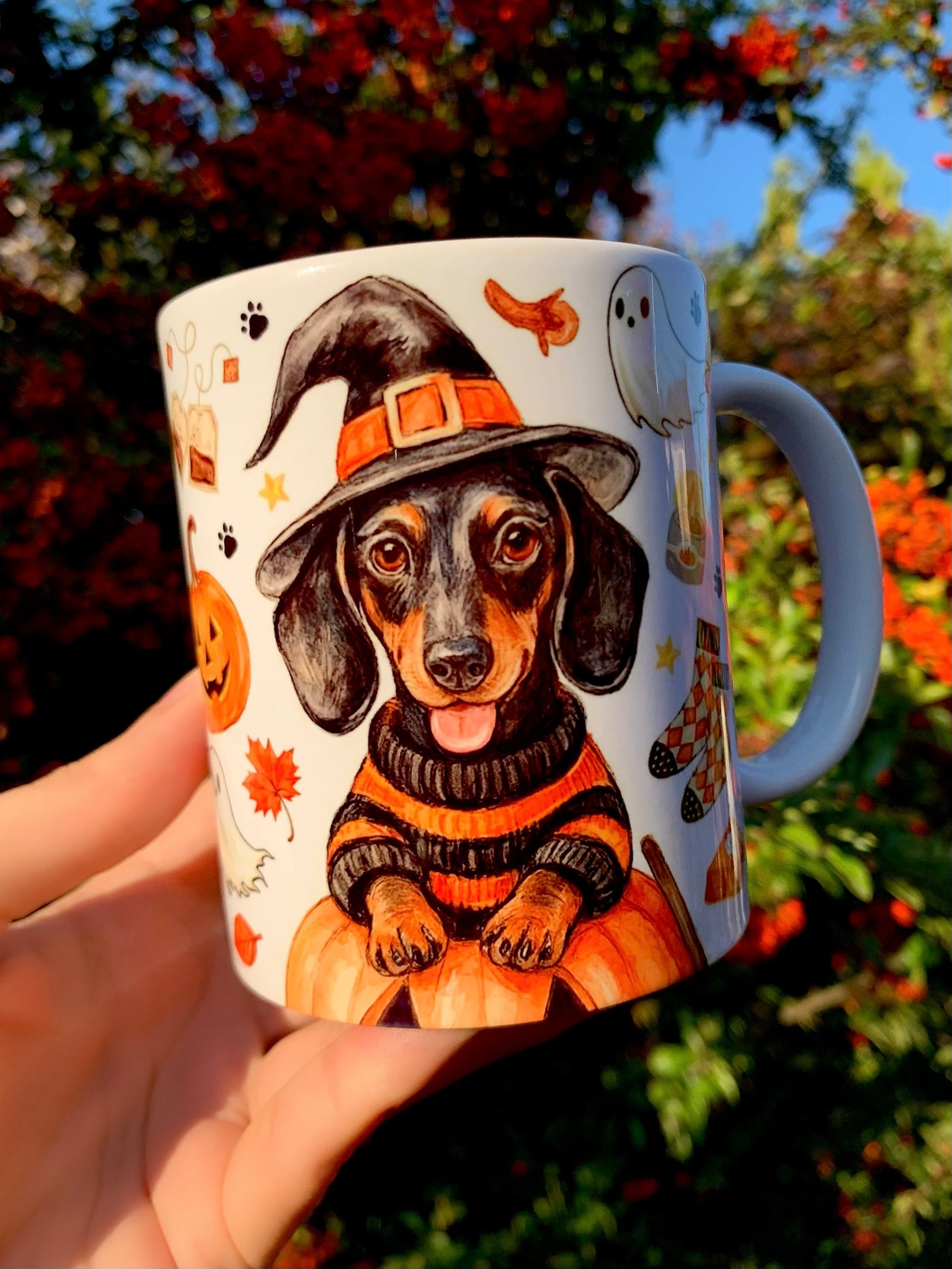 Őszi halloweeni hangulatú tacskós bögre, Pusztai Judit iparművész kézzel rajzolt és festett cser tacskó mintájával, boszorkánykalappal és tökös motívumokkal, egyedi kézműves ajándék.