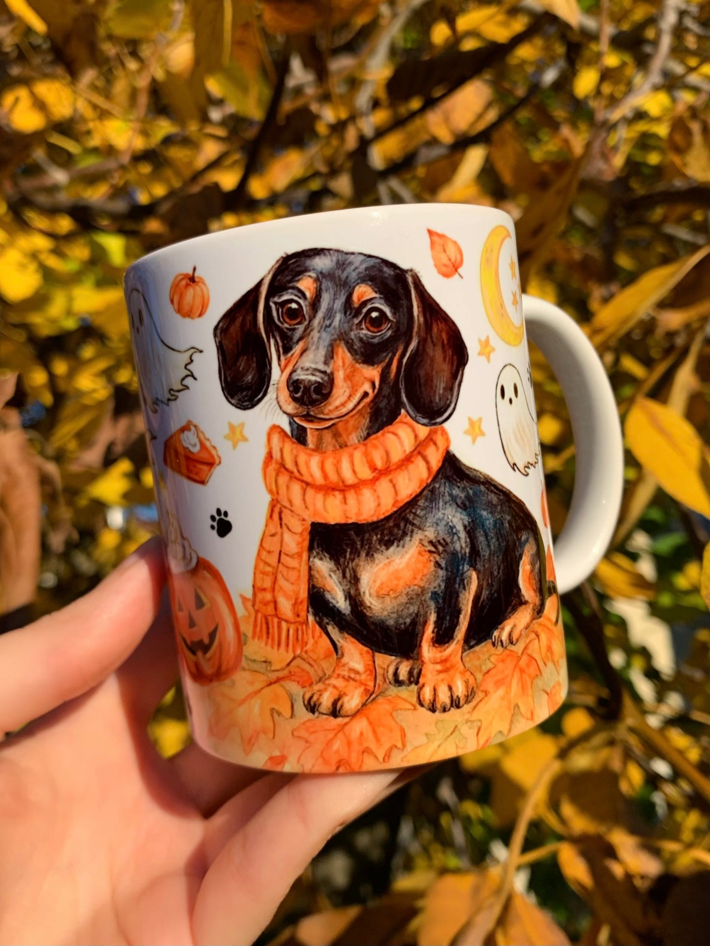 Prémium kézzel festett tacskós bögre, amelyet Pusztai Judit iparművész illusztrációi díszítenek. 🎨 Halloweeni szellemek, sütőtökök és őszi levelek idézik az ünnepi hangulatot. 🐾