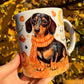 Kézzel festett, őszi tacskós bögre, amelyen barátságos cser tacskó, sütőtökök, szellemek és levelek díszítik a bögrét. 🍂🎃 A legszebb kézműves kutyás ajándék kávézós őszi napokra.