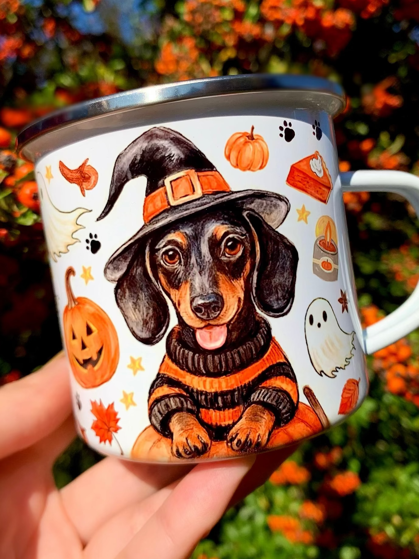 Halloweeni tacskós fém bögre kézzel festett tacskó illusztrációval pumpkin tökös, boszis és szellemes őszi mintákkal. Akvarelles cser tacskó, narancssárga tökök, szellemek, őszi levelek, fahéjas csiga és makkok díszítik a prémium kutyás bögrét. Egyedi őszi ajándék tacskó gazdiknak.