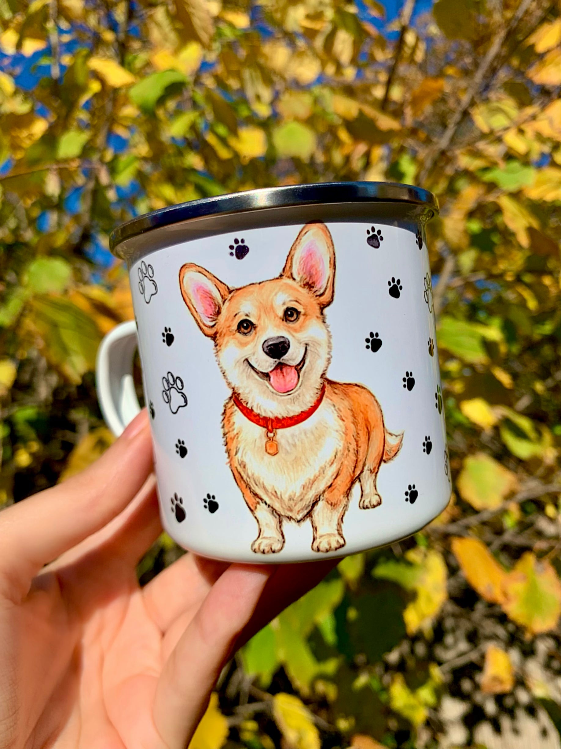 Corgi kutyás fém bögre kézzel festett illusztrációval, amely a fajta barátságos, játékos természetét idézi meg. Pusztai Juci egyedi grafikáján a Corgi kétféle nézetben is megjelenik: közelről megfestett arccal és teljes alakos pózban. A mancsos és szíves minták vidám hangulatot teremtenek.