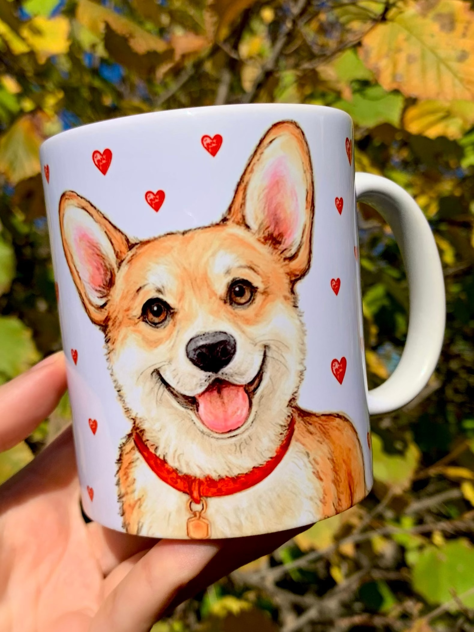 Corgi kutyás ajándékbögre, amely meleg tónusú, kézzel festett illusztrációkkal díszített. A mosolygó Corgi portré és az apró piros szívek a szeretet és vidámság üzenetét hordozzák – tökéletes ajándék minden Corgi rajongónak. ❤️