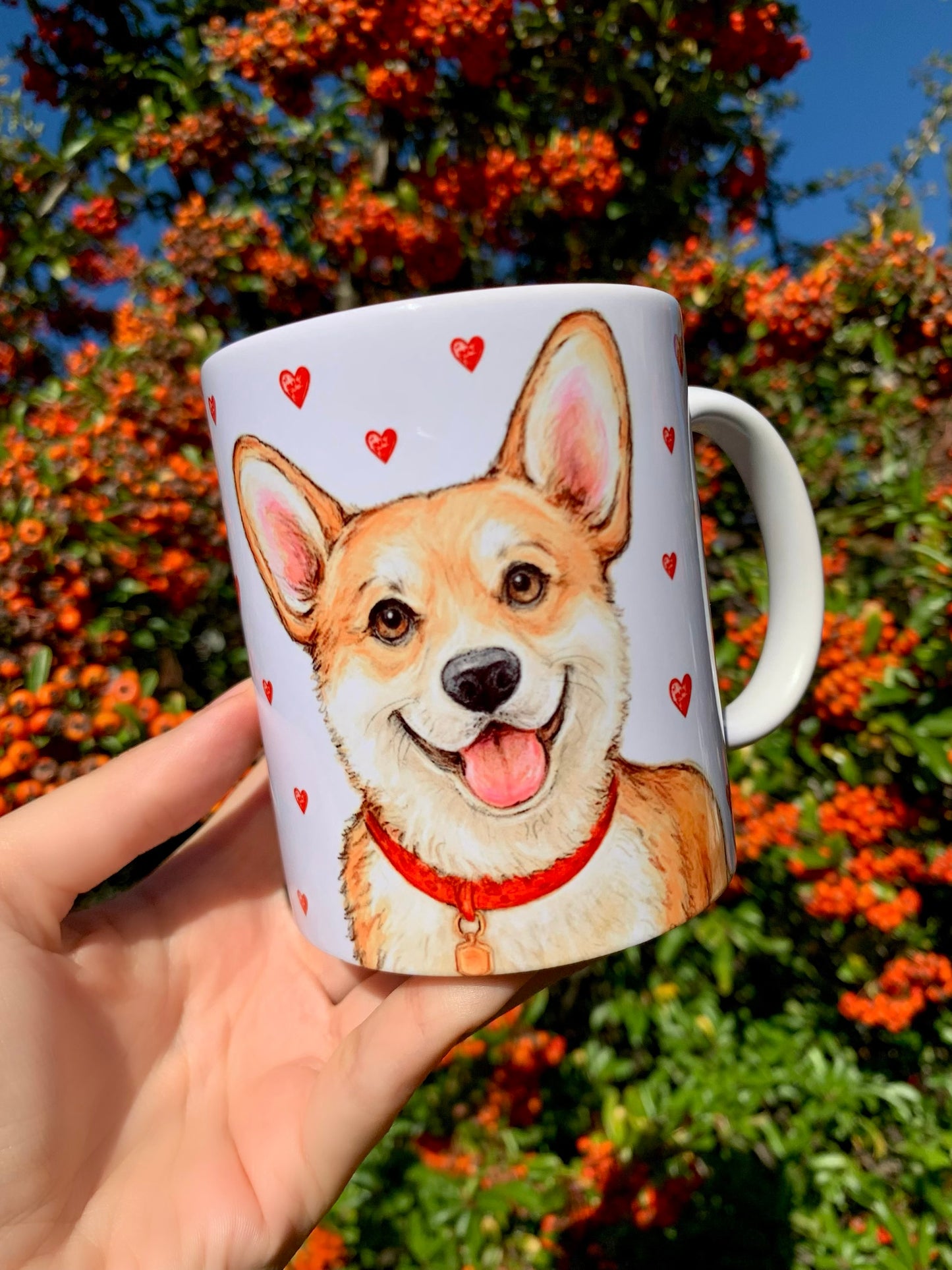 Prémium Corgi kutyás bögre, amelyen két különböző, kézzel rajzolt kutyagrafika látható: egyik oldalán közelről megfestett, részletgazdag Corgi arc, a másikon egész alakos, mosolygó kutya. A szívecskés háttér finom, akvarellhangulatú dekoráció. ☕🐾