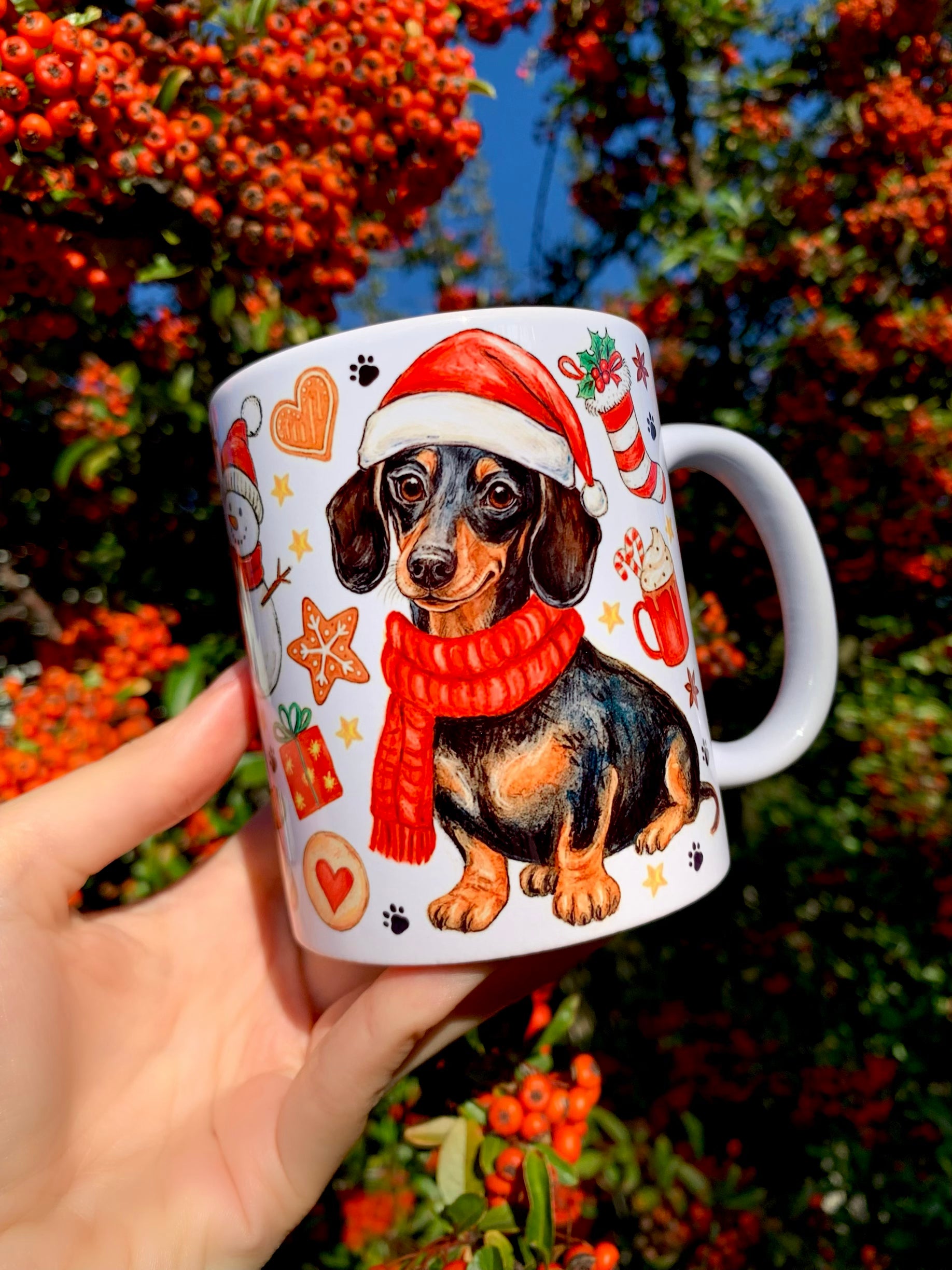 Kézműves, karácsonyi tacskós bögre mézeskalács és ünnepi díszek mintájával. A cser tacskó mikulássapkában mosolyog a bögréről. Prémium kutyás ajándék karácsonyi hangulathoz.