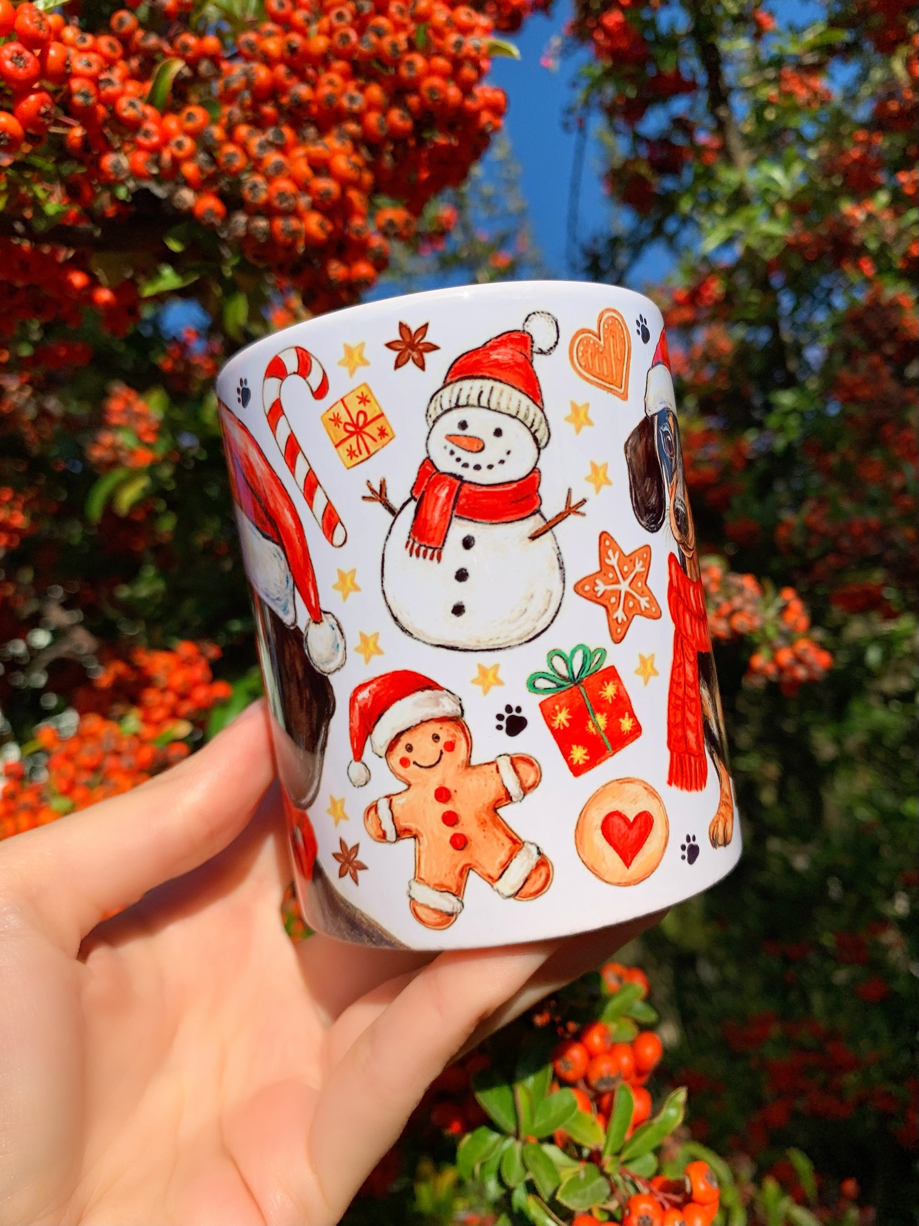 Cser tacskót ábrázoló karácsonyi kerámia bögre, kézzel festett részletgazdag illusztrációval. A háttérben karácsonyi cukorkák és harangok láthatók. Kutyabarátok és tacskó rajongók kedvenc ünnepi bögréje.