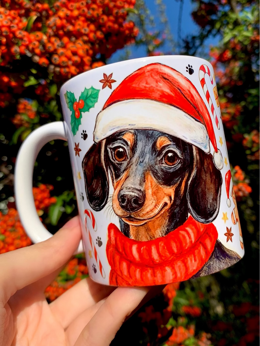 Kézzel festett, karácsonyi tacskós kerámia bögre cser színű tacskóval, mikulássapkában, mézeskalács figurákkal, karácsonyi cukorkákkal és piros-zöld ünnepi motívumokkal díszítve. Az iparművészeti minőségű, egyedi magyar kézműves bögre Pusztai Juci részletgazdag akvarell illusztrációját viseli, egyik oldalon kinagyított tacskóportréval, másik oldalon egész alakos tacskóval. Prémium tacskós ajándék karácsonyra tacskó gazdiknak, kutyabarátoknak, akik szeretik az ünnepi hangulatú, minőségi kutyás termékeket.