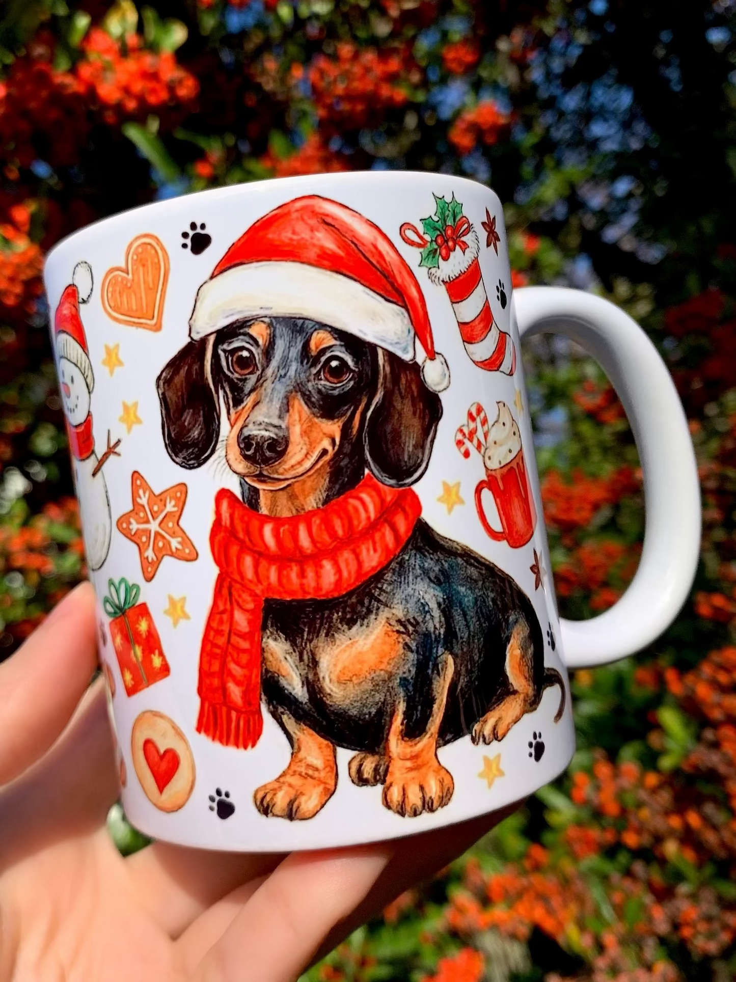 Karácsonyi tacskós kerámia bögre kézzel festett cser tacskó grafikával és apró ünnepi motívumokkal. A bögrén portré és egész alakos tacskó illusztráció is megjelenik. Egyedi magyar kézműves ajándék tacskó gazdiknak karácsonyra.