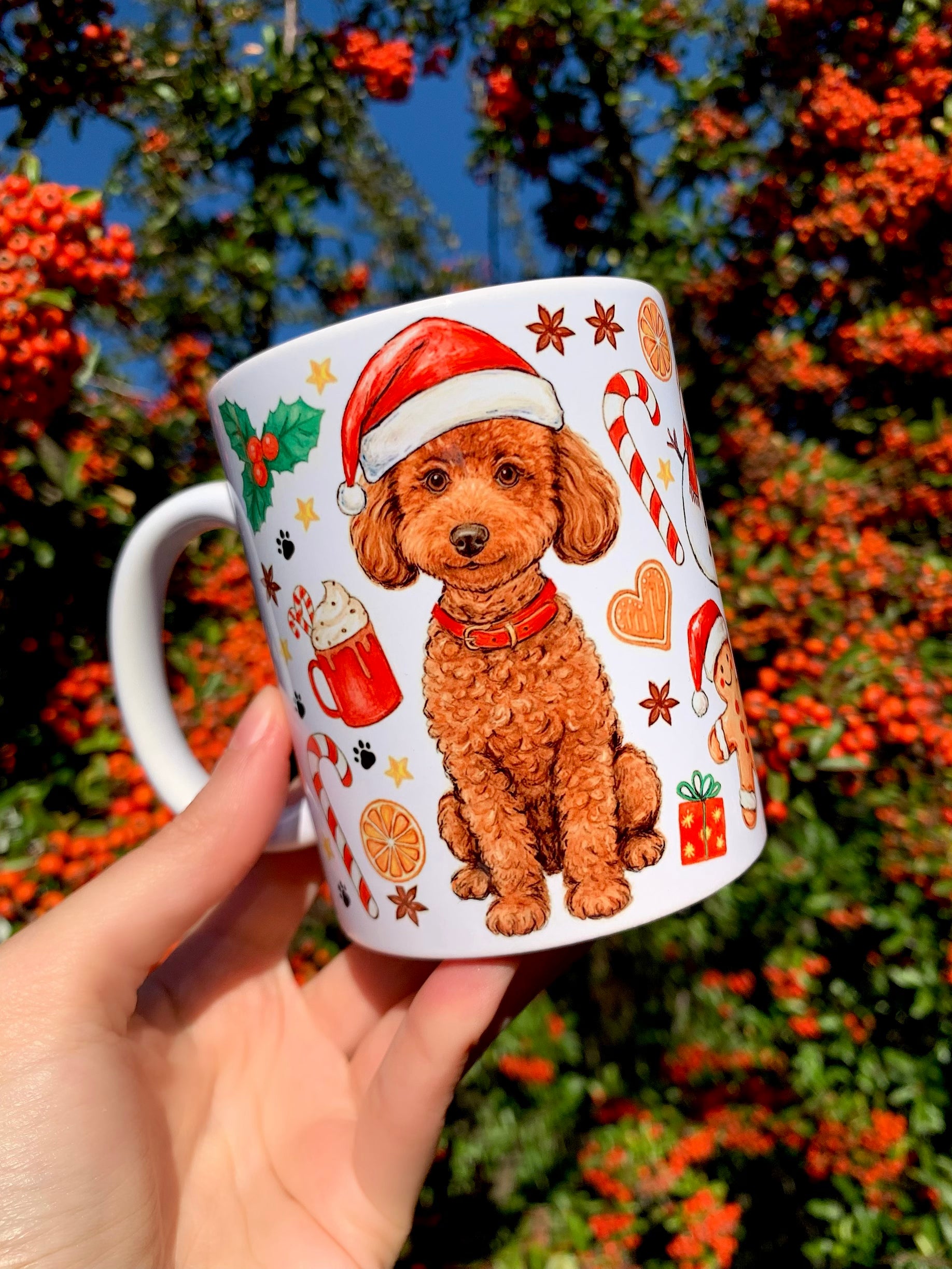 Toy Poodle karácsonyi kerámia bögre – kézzel festett uszkár portréval és ülő teljes alakos kutyus grafikával. A bögrét finom akvarell textúrák, mézeskalácsok és piros-zöld ünnepi minták díszítik. Egyedi kutyás karácsonyi ajándéktárgy.