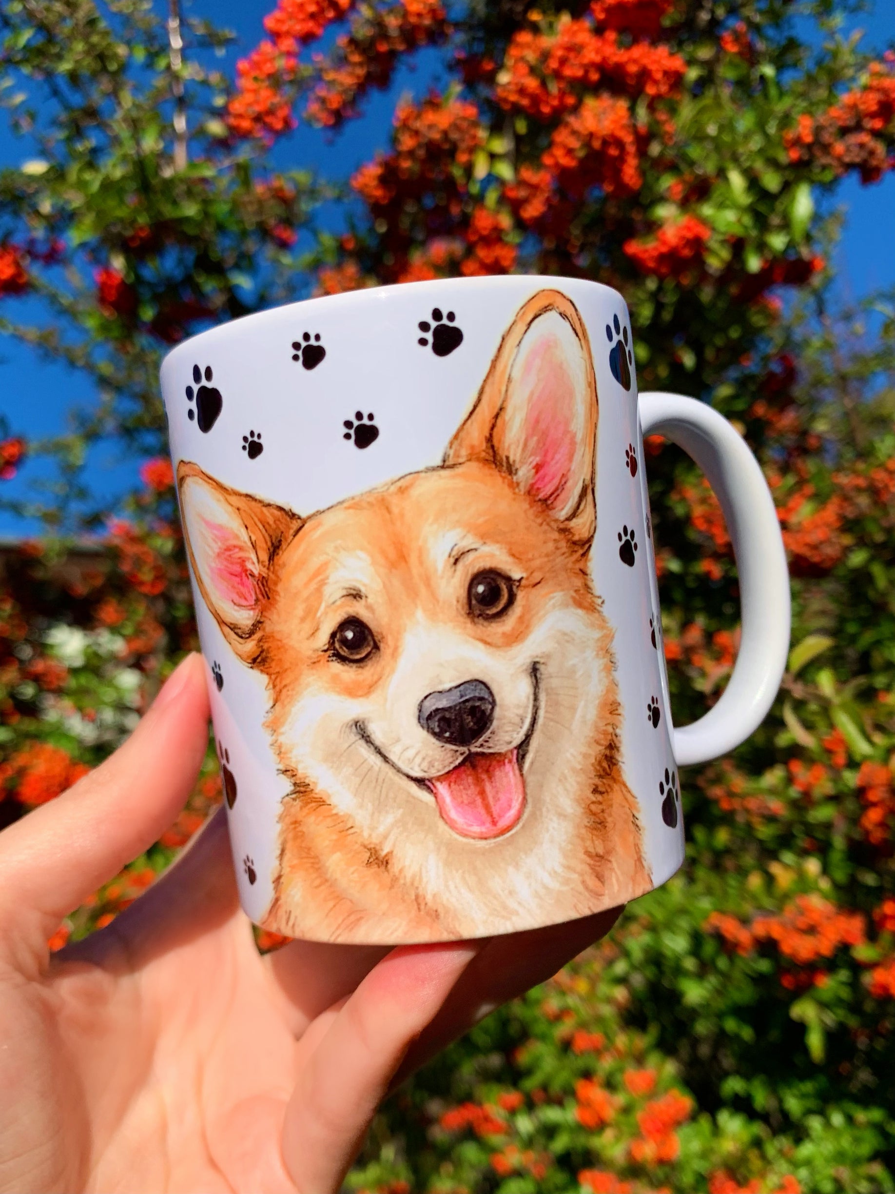 Kézzel rajzolt Corgi illusztrációval díszített bögre, akvarell részletekkel és mancs mintás háttérrel. A Corgi portré kedves tekintettel néz ránk, a másik oldalon álló kutya látható. Prémium tacskós ajándék kutyarajongóknak.