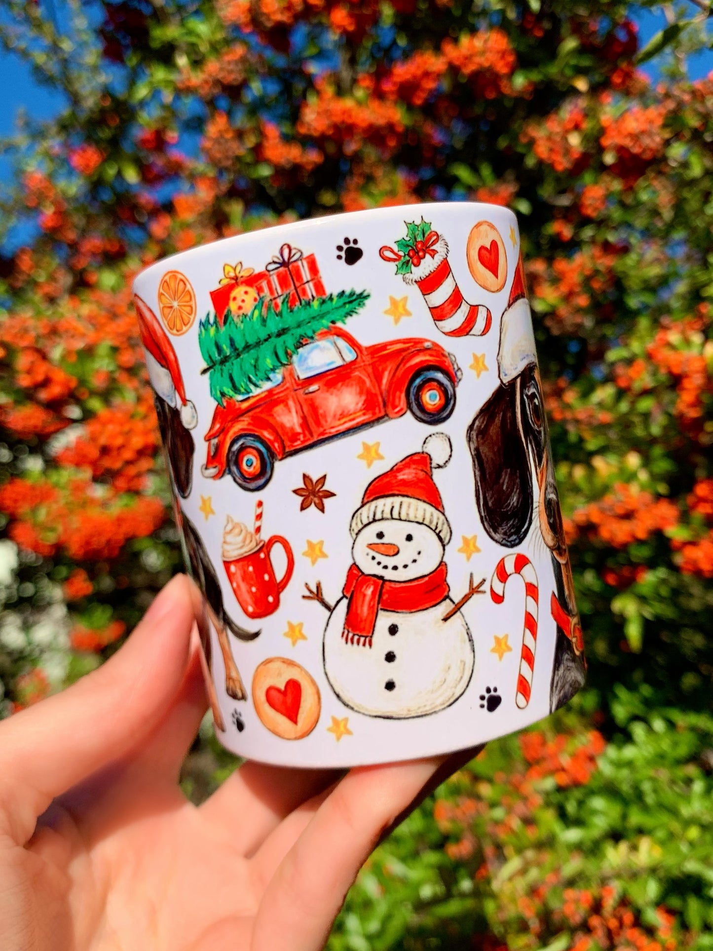 A bögrén lágy akvarelltechnikával festett tacskó szerepel ünnepi motívumok között. A piros nyakörv és karácsonyi elemek élénk színt visznek a kompozícióba. Egyedi, kézzel készült hatású kerámia ajándék.