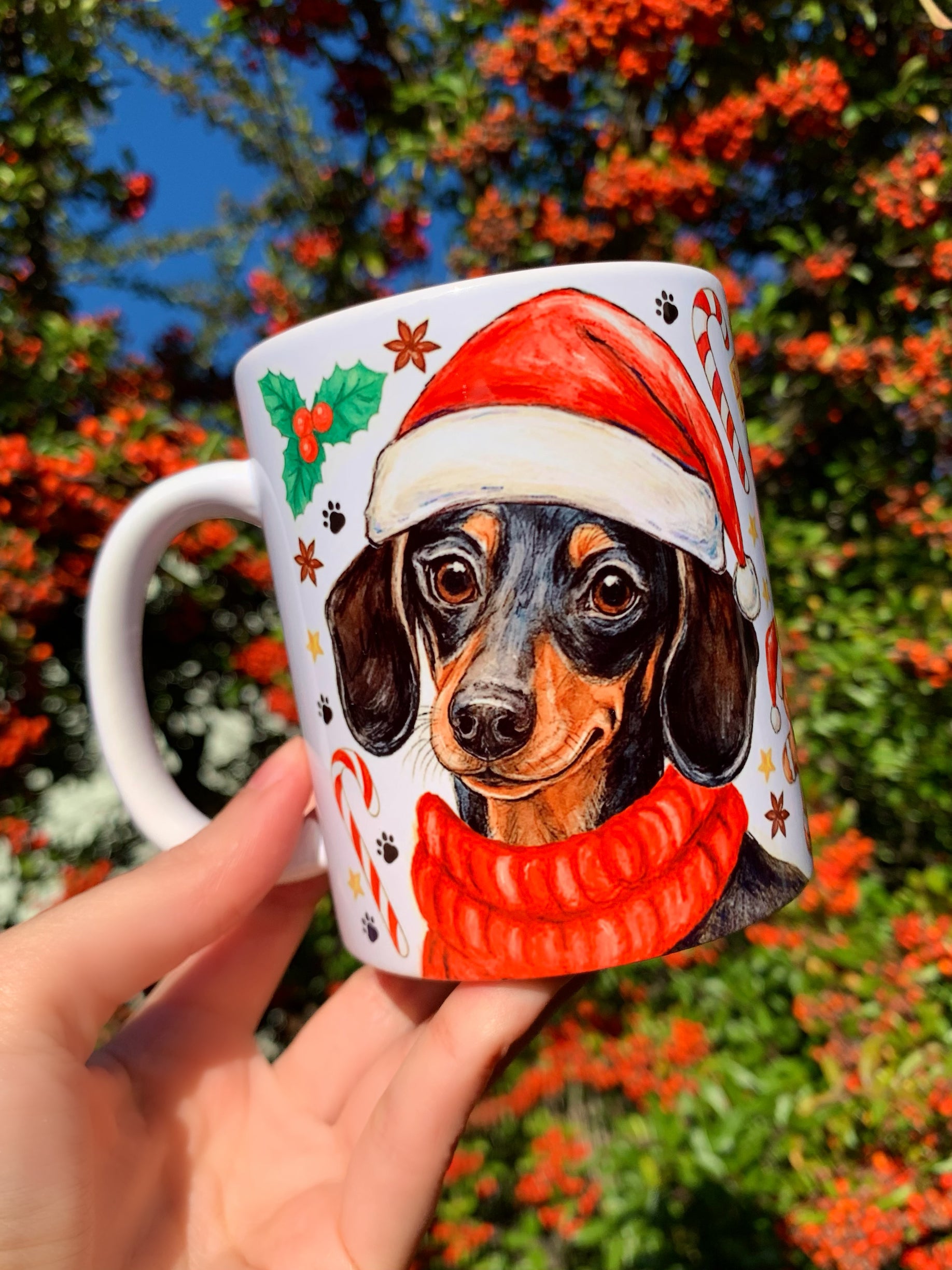 Kézzel festett tacskós karácsonyi bögre Pusztai Juci illusztrációival. A cser tacskó portréja és egész alakos változata is szerepel rajta. Egyedi, prémium minőségű ajándék kutyás szeretteknek.