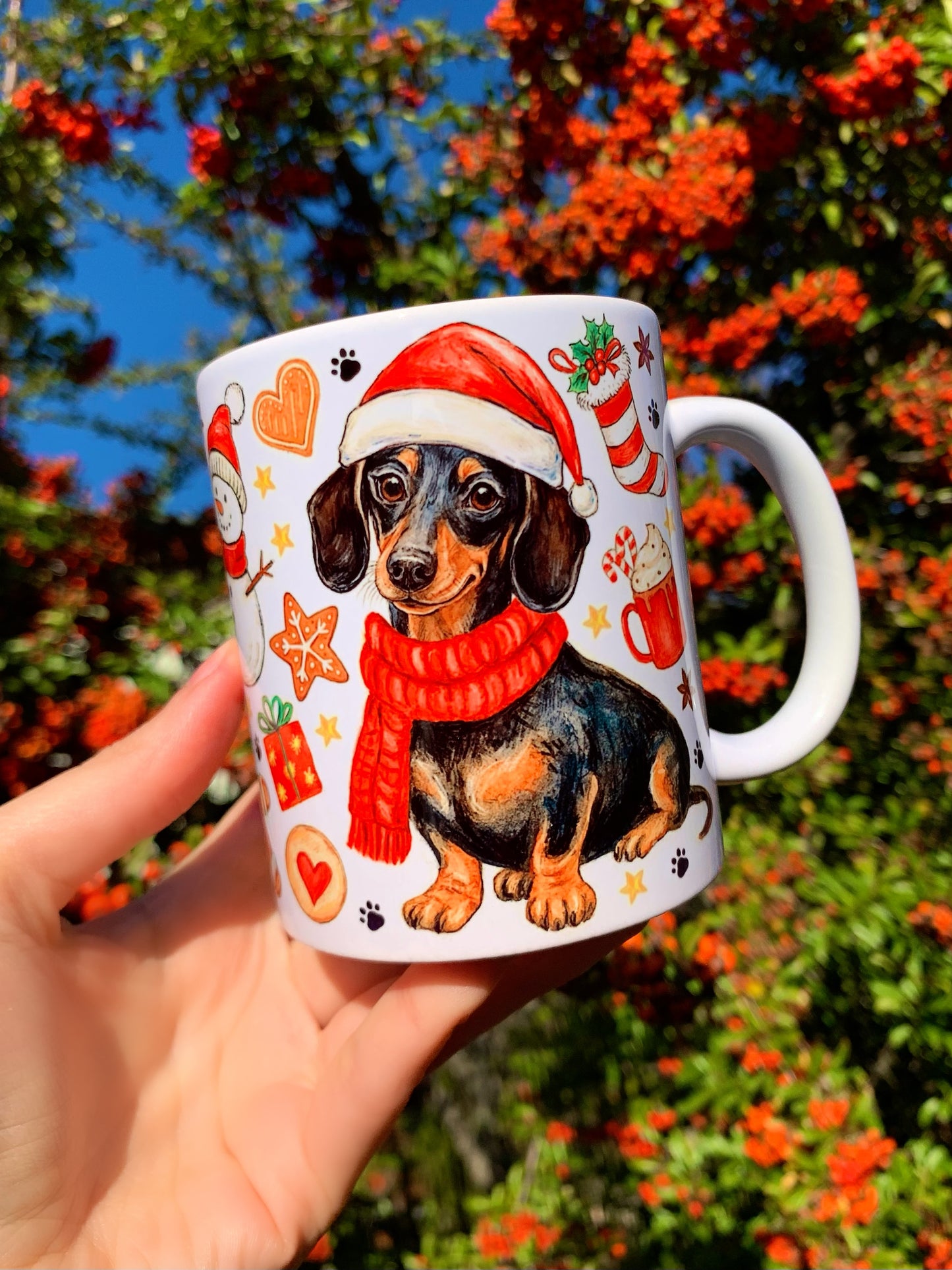 Ünnepi hangulatú tacskós kerámia bögre részletgazdag, kézzel rajzolt tacskó portréval és karácsonyi elemekkel. Cser tacskó mikulássapkában, szerethető, bájos grafikával. Ideális ajándék kutyabarátoknak karácsonyra.