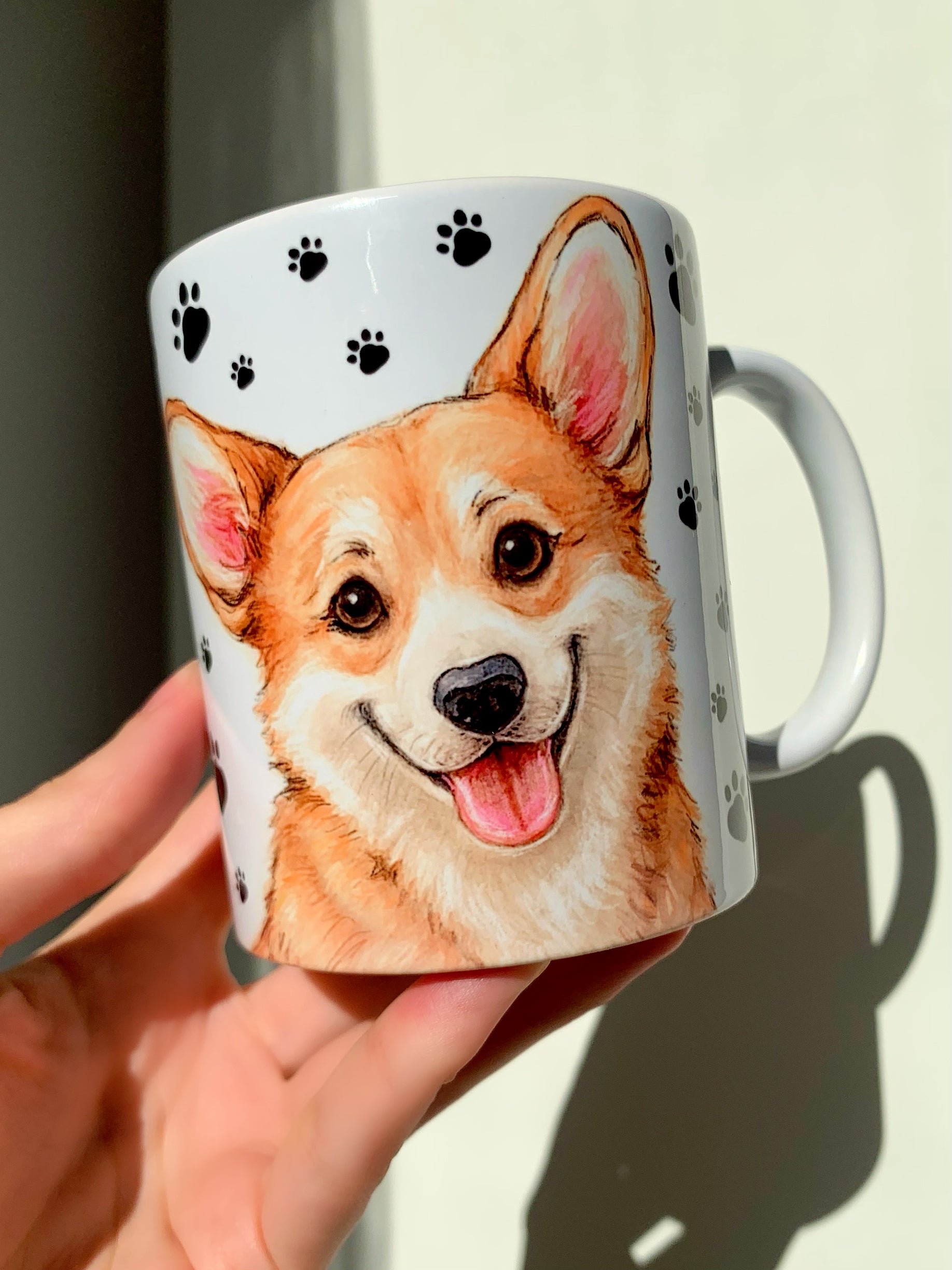 Egyedi kézműves Corgi kutyás bögre, részletgazdag portréval és teljes alakos illusztrációval. A kutyus körül apró, kézzel rajzolt mancs minták láthatók. Tökéletes reggeli kávés vagy teázós kiegészítő gazdiknak.