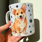 Corgi kutyás kerámia bögre kézzel festett illusztrációval, amely a fajta barátságos, játékos karakterét ragadja meg. Mancsos háttér és kétféle Corgi minta díszíti, ideális ajándék kutyabarátoknak.