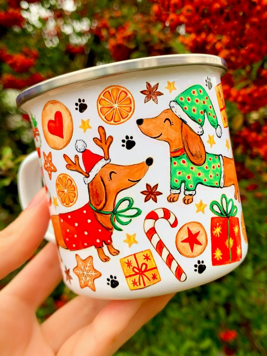 Karácsonyi tacskós fém bögre kézzel festett, többféle színű tacskó mintával: cser, fekete-cser, vörös és drótszőrű tacskó ünnepi motívumokkal. Mézeskalács, cukorpálca, fenyőág, csengő és piros–zöld karácsonyi dekorok díszítik. Prémium kutyás ajándék tacskó gazdiknak.