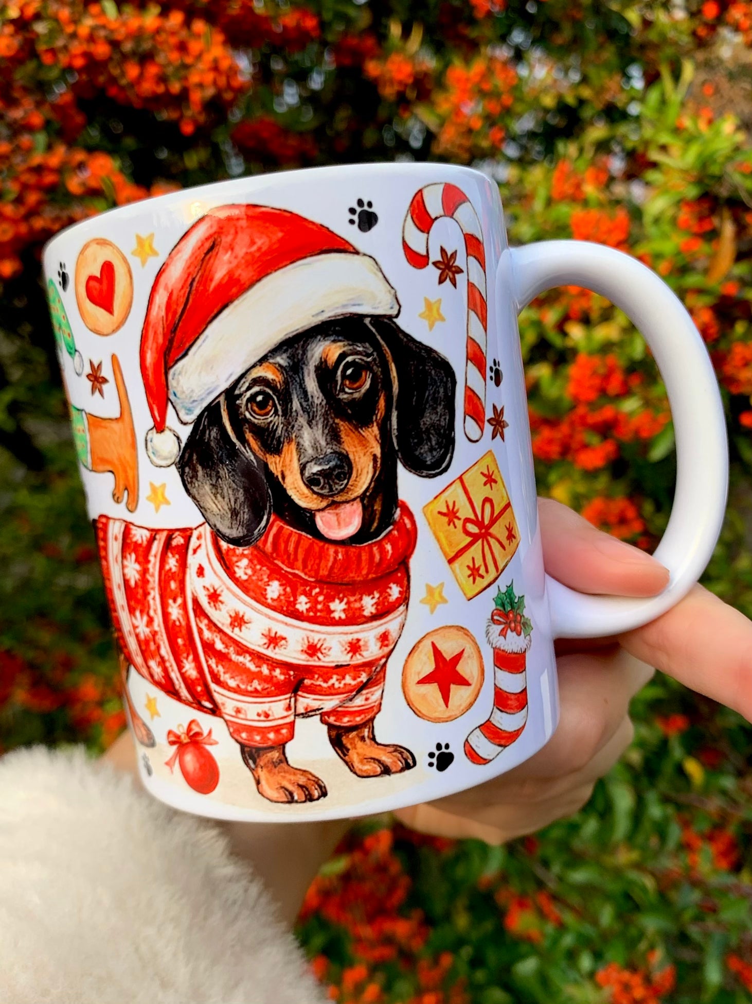 Karácsonyi tacskó minta bögrén, apró ismétlődő tacskó figurákkal. Téli ruhás kutyák, karácsonyi díszek és meleg ünnepi színek láthatók. Kézműves tacskós ajándék gazdiknak.