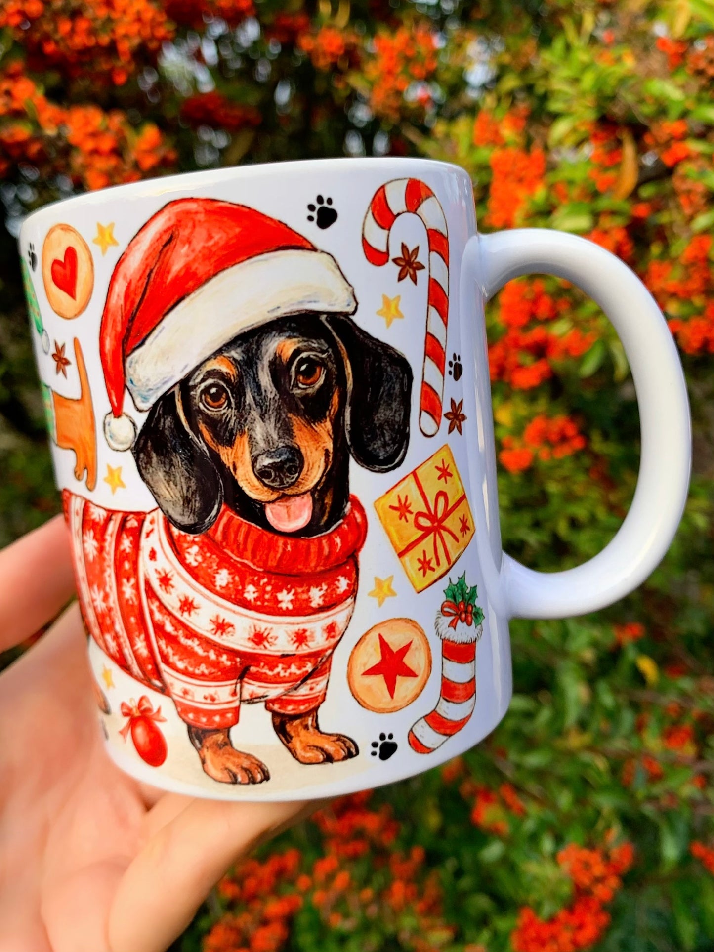 Karácsonyi tacskós bögre oldalnézetből, kézzel festett részletekkel. Mézeskalács figurák és ünnepi díszek teszik teljessé a mintát. Kézműves kutyás ajándék bögrén.