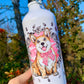 Közelkép a mosolygó Corgi arcáról fém kulacson, rózsaszín virágmintás és gyümölcsös akvarell háttérrel, részletes kézzel rajzolt grafikával.