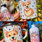 Kézzel festett Corgi illusztráció Pusztai Juci iparművésztől, fém bögrére megálmodva. Az egyik oldalon részletgazdag Corgi fej, a másikon vidáman álló kutya látható. Az apró mancs és szív minták egyedi, szeretetteljes hangulatot adnak a prémium minőségű kutyás ajándéknak.