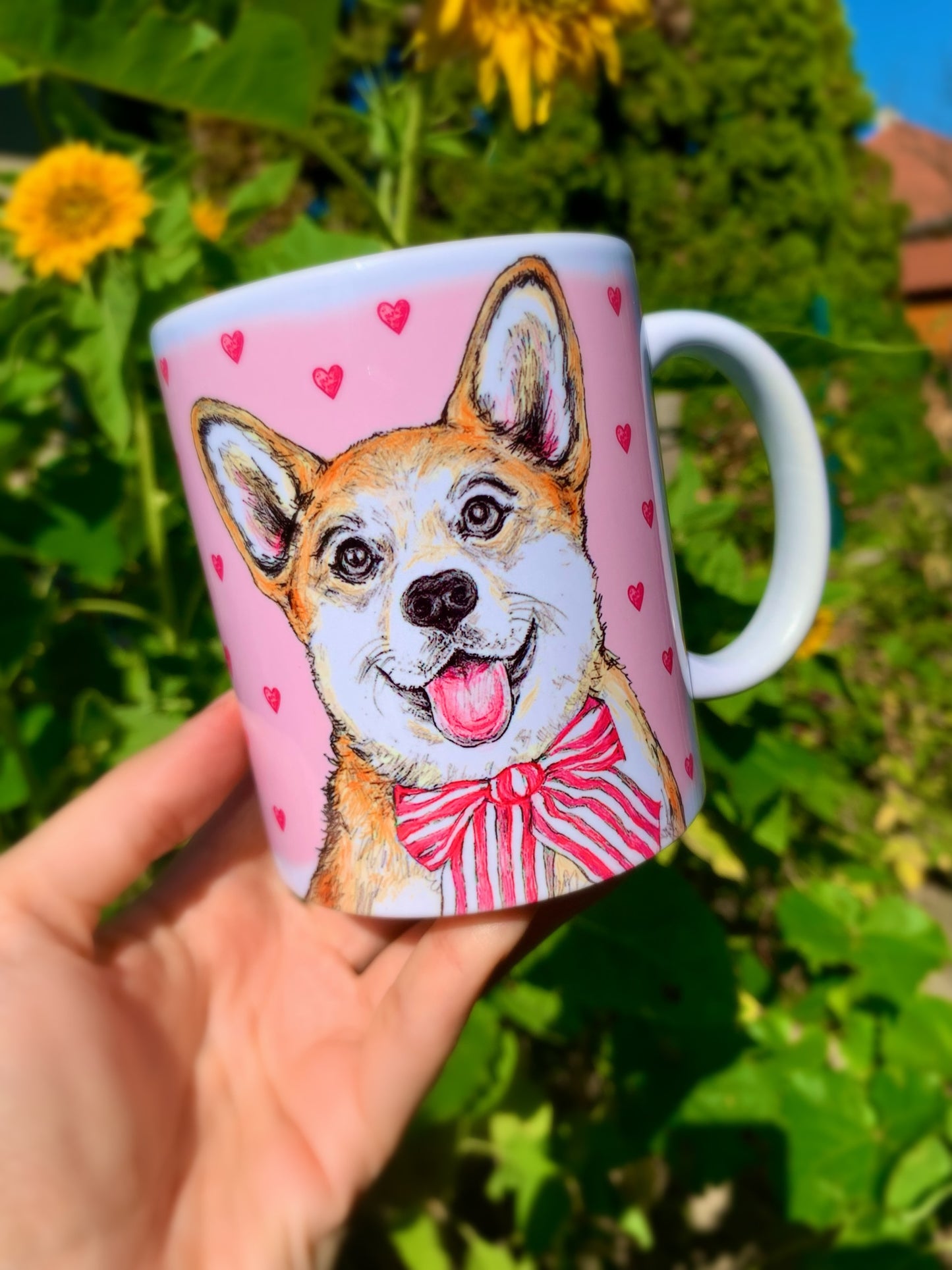 Kedves, mosolygó világosbarna-fehér Corgi illusztrációval díszített kerámia bögre, rózsaszín szív mintákkal és kézzel festett akvarell részletekkel.