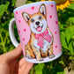 Kerámia bögre nagyított, kézzel festett világosbarna-fehér Corgi arcképpel, mosolygó tekintettel és rózsaszín szív mintákkal, fehér háttérrel.