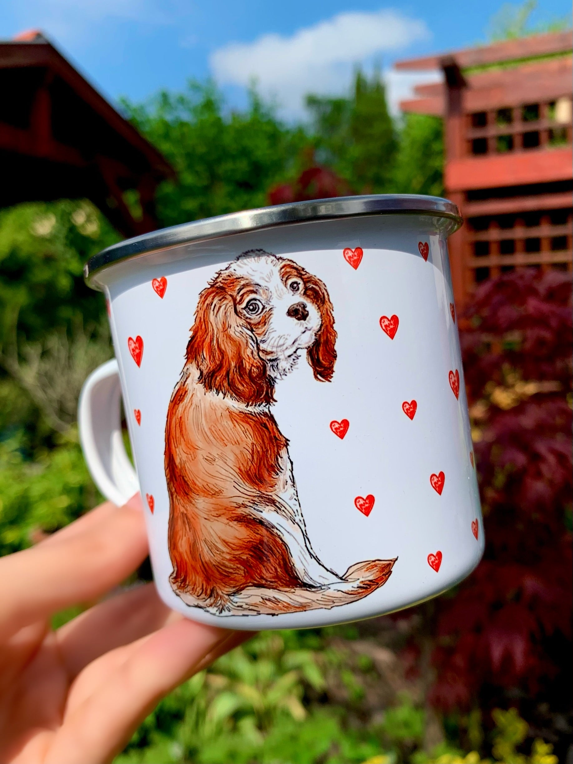 Barna-fehér cavalier spániel portré közelről, fém bögrén