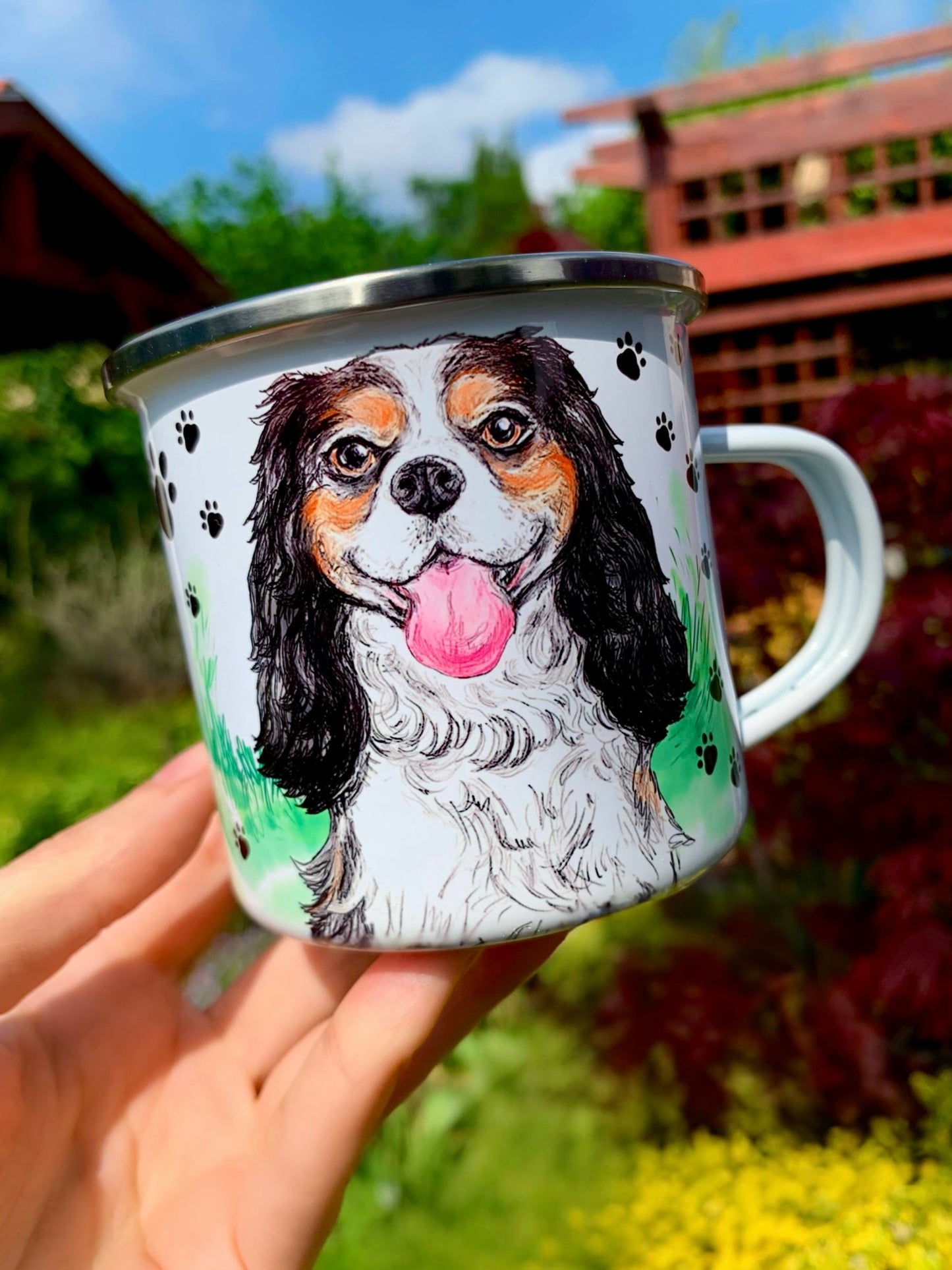 Fém bögre kézzel festett barna–fekete–fehér Cavalier King Charles spániel mosolygó portréjával, fekete mancs mintás fehér háttérrel, prémium ajándék
