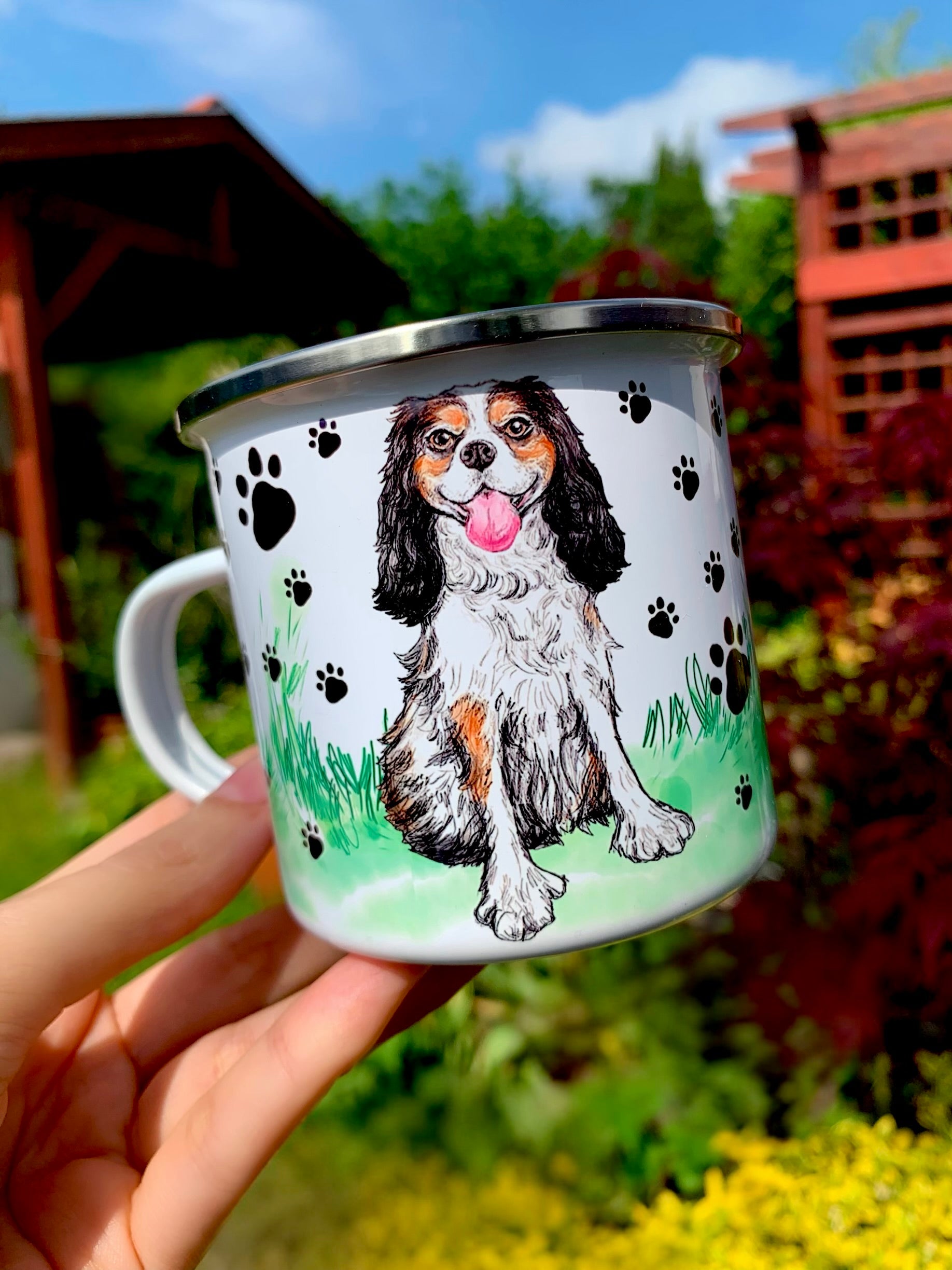 Ülő, mosolygó Cavalier spániel kézzel festett portréja kerámia bögrén, barna–fekete–fehér színkombinációban, fekete mancsos fehér háttérrel