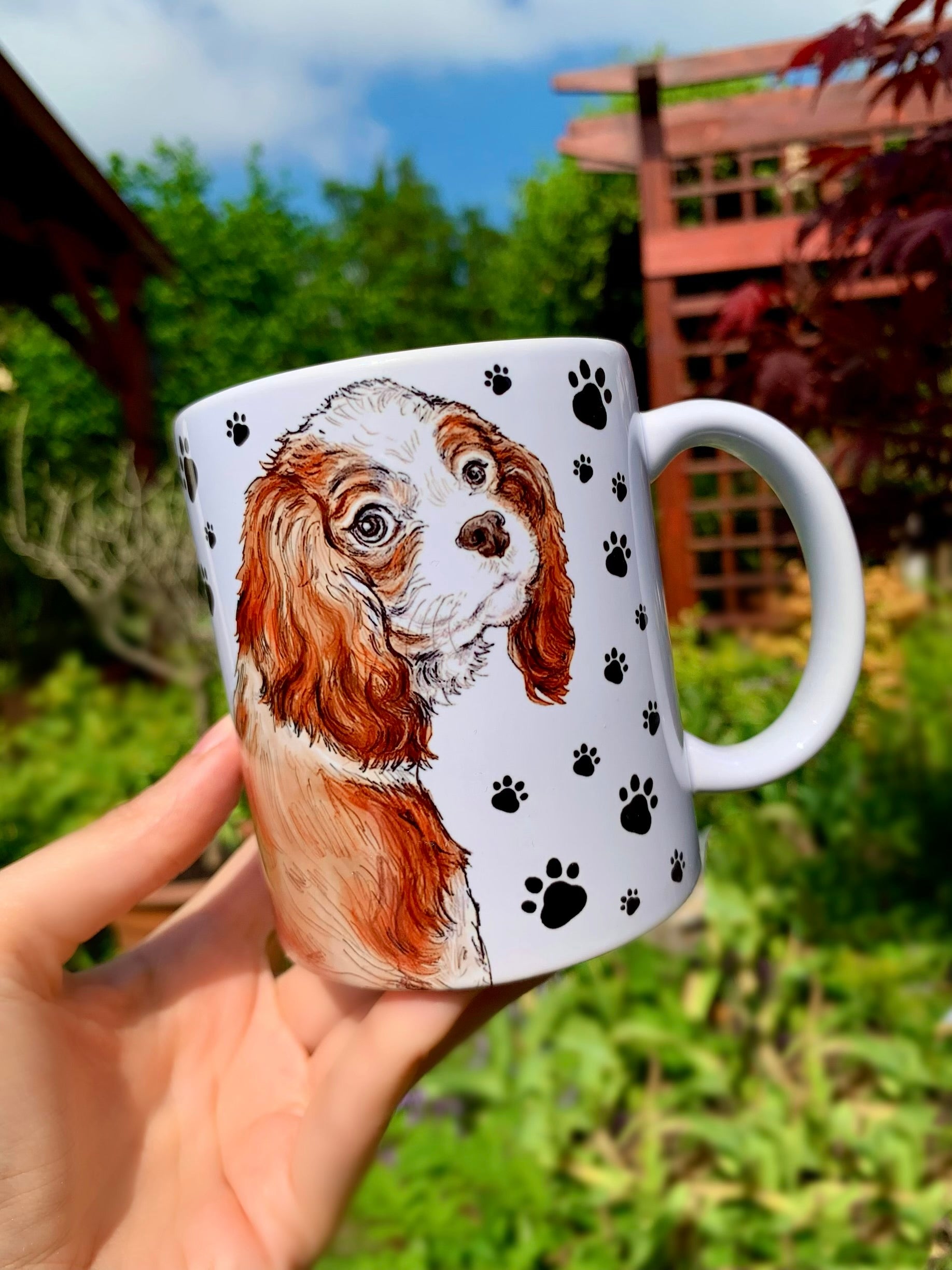 Kedves Cavalier spániel illusztráció kerámia bögrén, fekete mancs mintás háttérrel