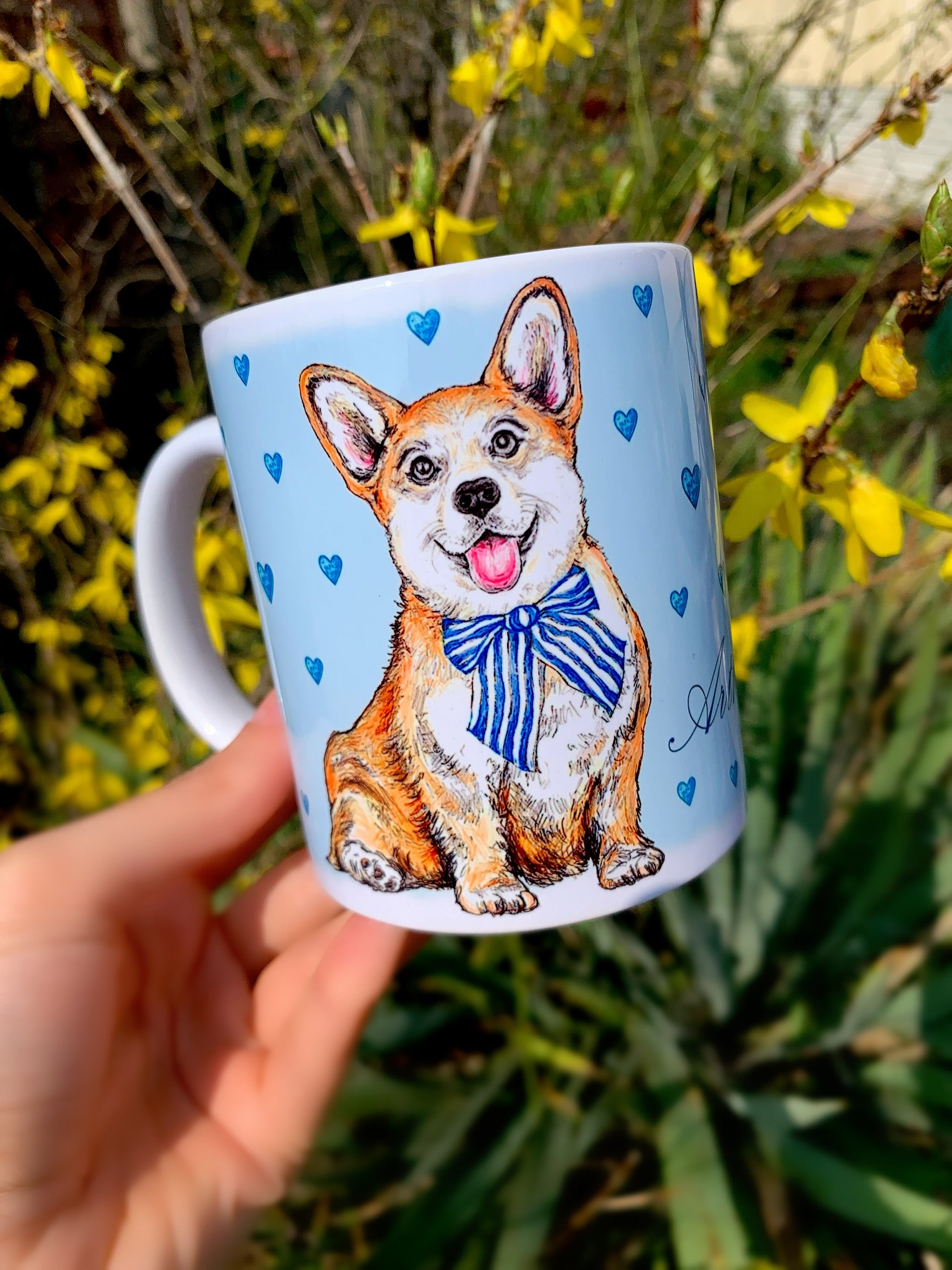 Kerámia bögre kinagyított, mosolygó Corgi fejes illusztrációval és kézzel festett világoskék szív mintákkal, fehér háttérrel.