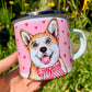 Fém bögre világosbarna-fehér Corgi illusztrációval, kézzel rajzolt és akvarellfestett részletekkel, rózsaszín szív mintákkal, fehér háttérrel.