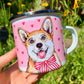 Fém bögre kézzel rajzolt, akvarellfestett világosbarna-fehér Corgi kutyával, nagy mosollyal és rózsaszín szív mintákkal, fehér háttérrel, részletgazdag grafikával.