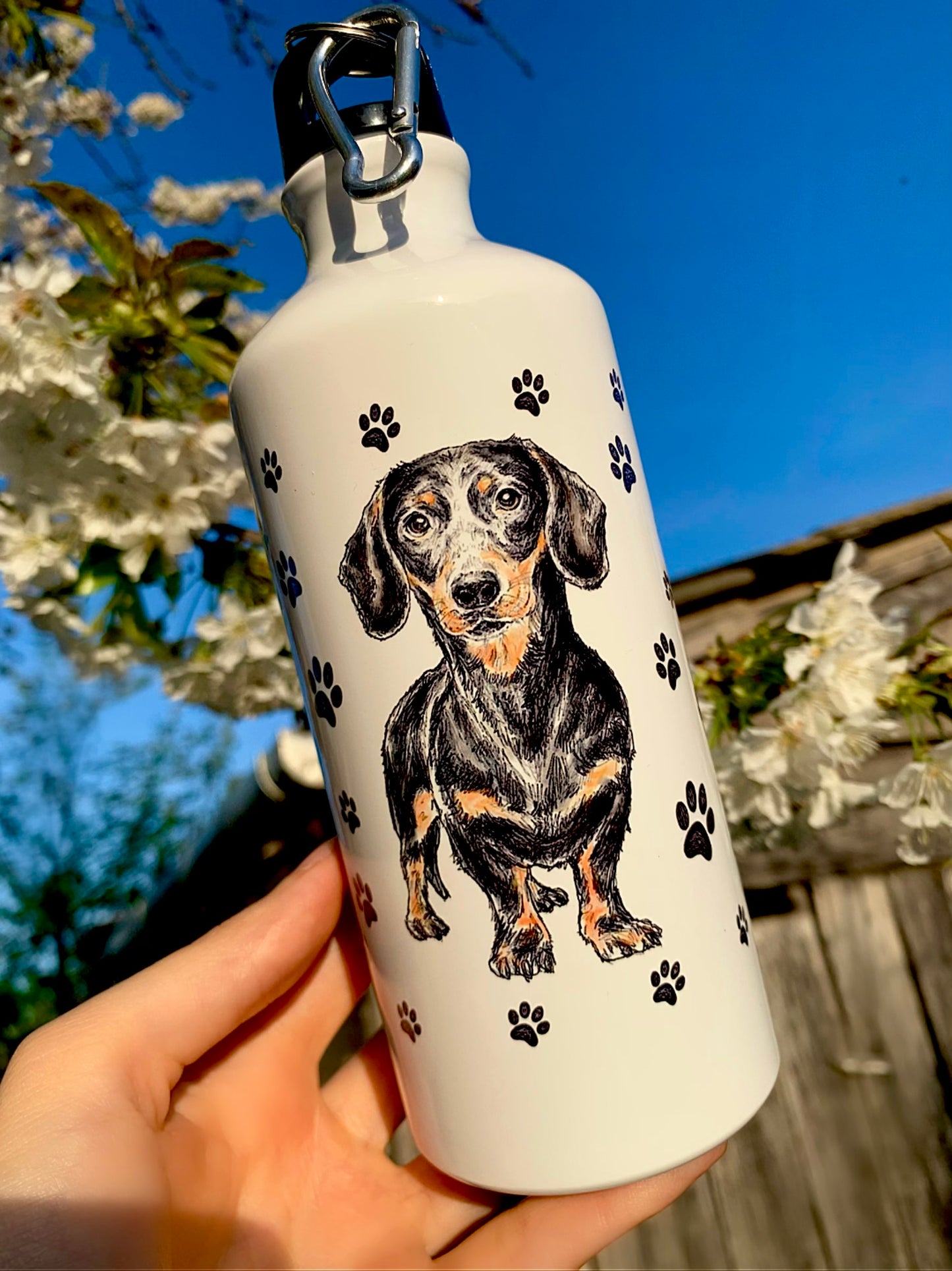 Ez a 600 ml-es tacskós fém kulacs kézzel rajzolt cser tacskó illusztrációval és játékos mancsos háttérmintával készült. Könnyű, tartós és ideális mindennapi használatra vagy túrázáshoz tacskó gazdiknak. Prémium, szerethető kutyás ajándék minden tacsi-rajongónak.
