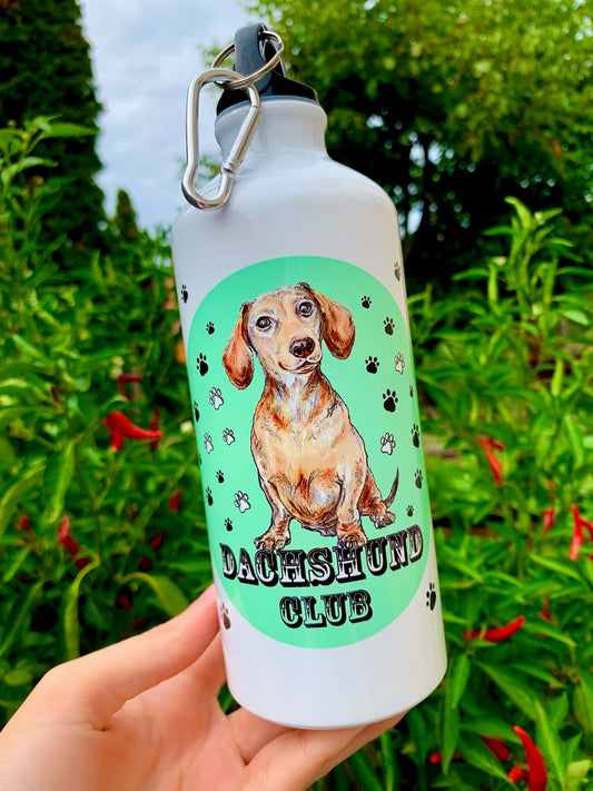 A tacskós kulacs színes, festett háttere modern, trendi megjelenést biztosít, amely kiemeli a kézzel rajzolt cser tacskó illusztrációt. 600 ml-es kapacitása miatt hosszabb utakra is ideális. Tacskó gazdiknak tervezett különleges, magyar műhelyben készült ajándék.