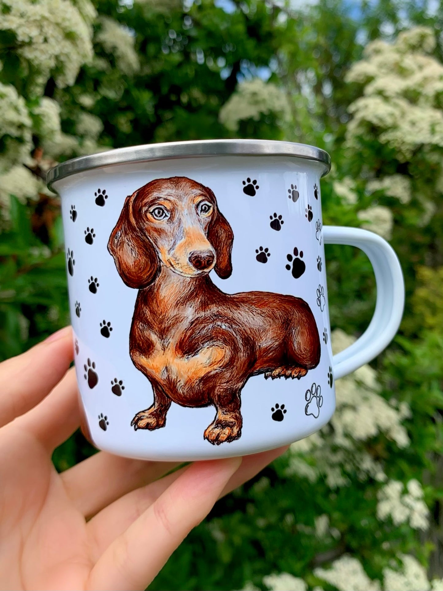 Kézzel festett csokibarna tacskó portré és fekete mancsnyomok díszítik ezt a prémium minőségű, könnyű, tartós, zománcozott fém bögrét.