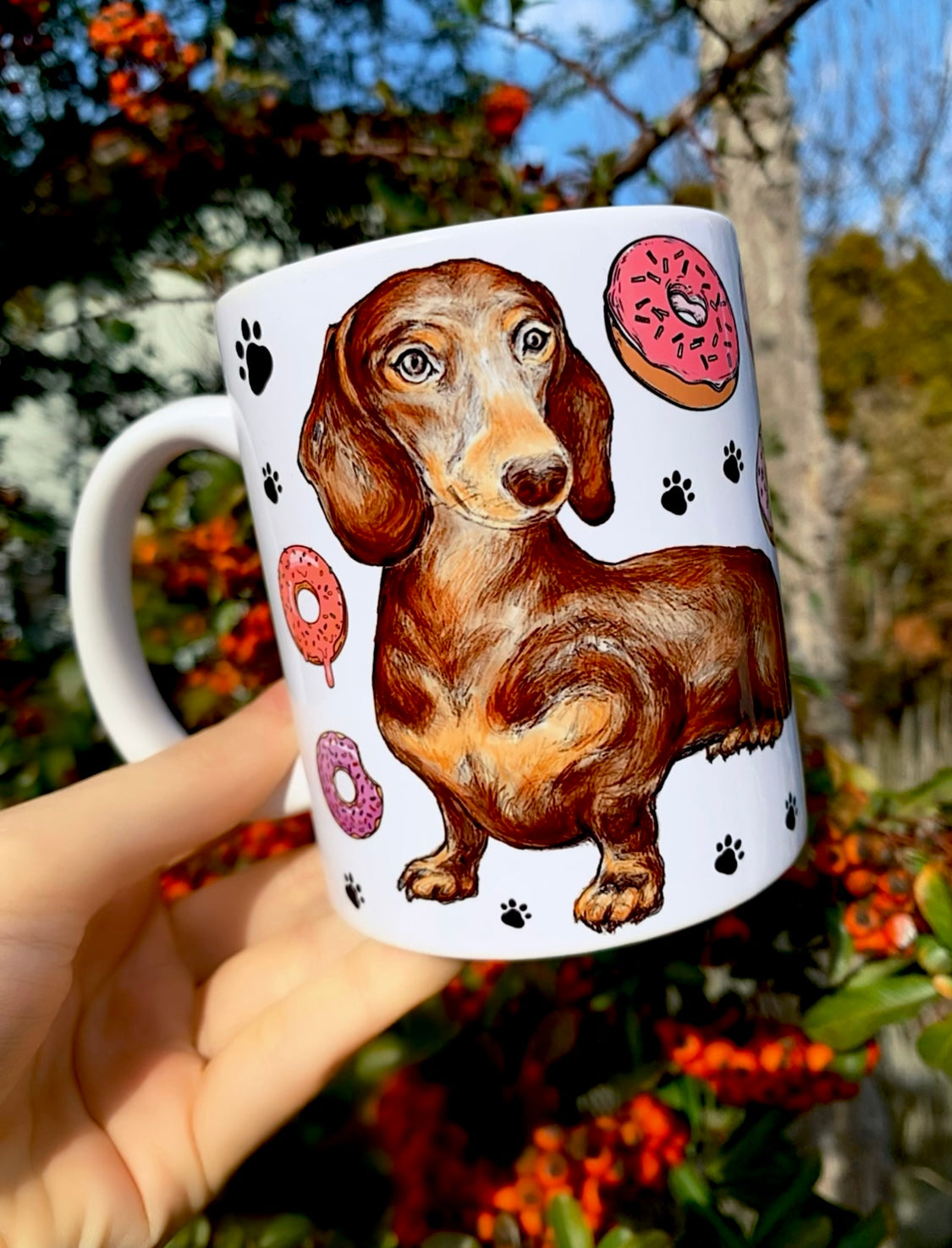 Tacskó kollekció kerámia bögréje – csokibarna kutya portré akvarelles részletekkel, fánkokkal és fekete mancs mintákkal, kézműves illusztrációval.