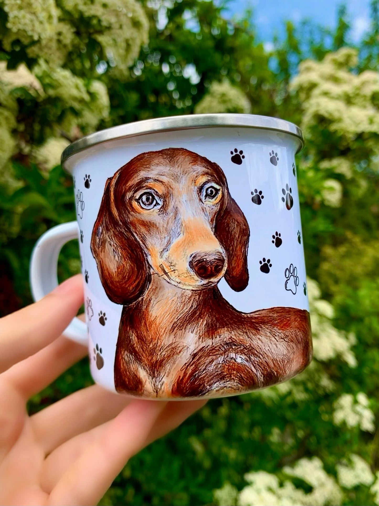 Részletgazdag, kézzel festett csokoládészín tacskó portré akvarellhatású árnyalással, vidám fekete mancsnyomokkal – praktikus fém bögre formában.