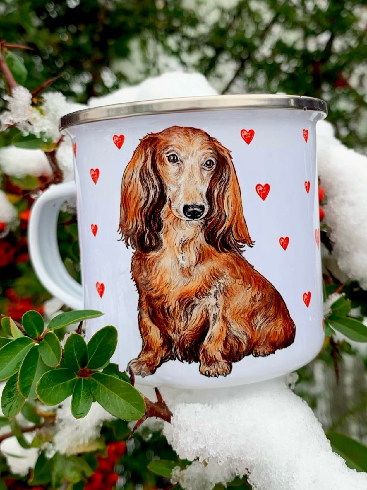 Kézzel festett hosszúszőrű tacskó portré piros szív mintákkal díszített prémium fém bögrén, meleg barna és arany árnyalatokkal.