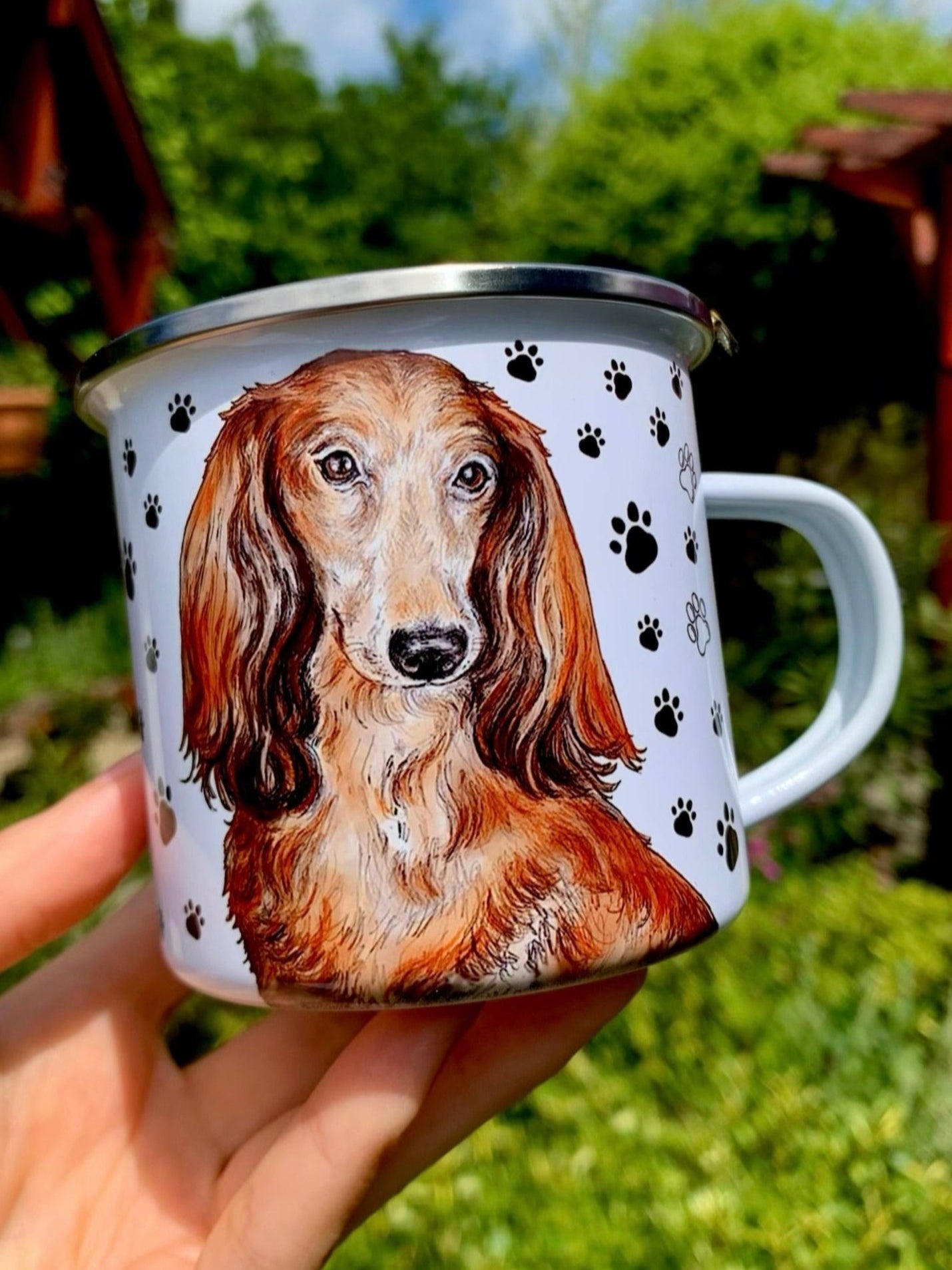 Stílusos hosszúszőrű tacskós fém bögre, részletgazdag kézi festés és játékos fekete mancsnyomos díszítés – ajándéknak is tökéletes.