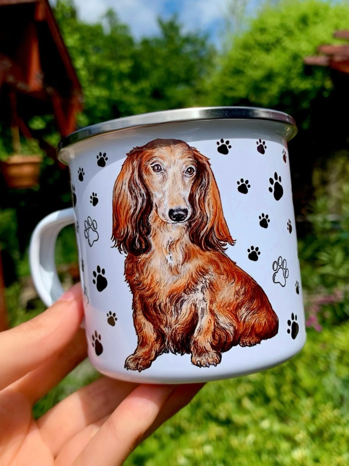 Kézzel festett hosszúszőrű tacskó portré fekete mancsnyomokkal díszített prémium fém bögrén, selymes barna szőrárnyalatokkal.